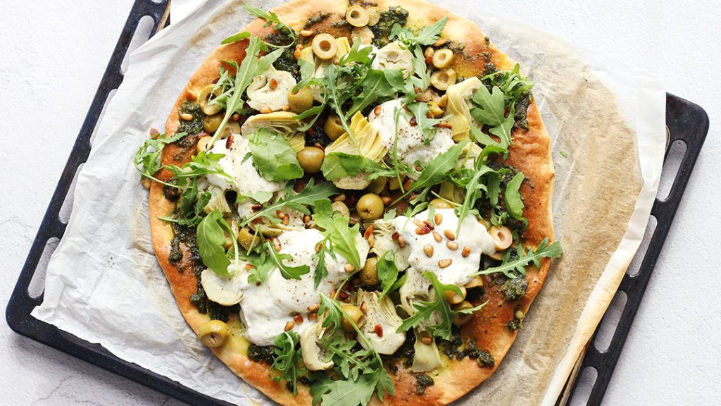 Vers gebakken artisjok pizza met romige spinazie-roomkaastoping en mozzarella, klaar om te serveren